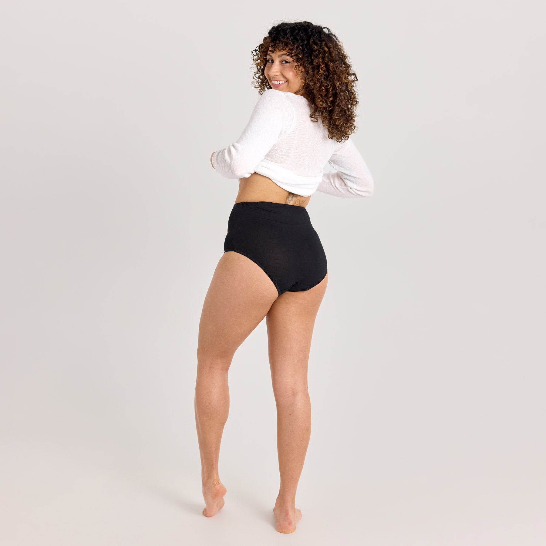 Takaapäin kuvattuna mustat naisten maxi-alushousut. Korkeavyötäröiset pehmeät alushousut on valmistettu Kangasalla.