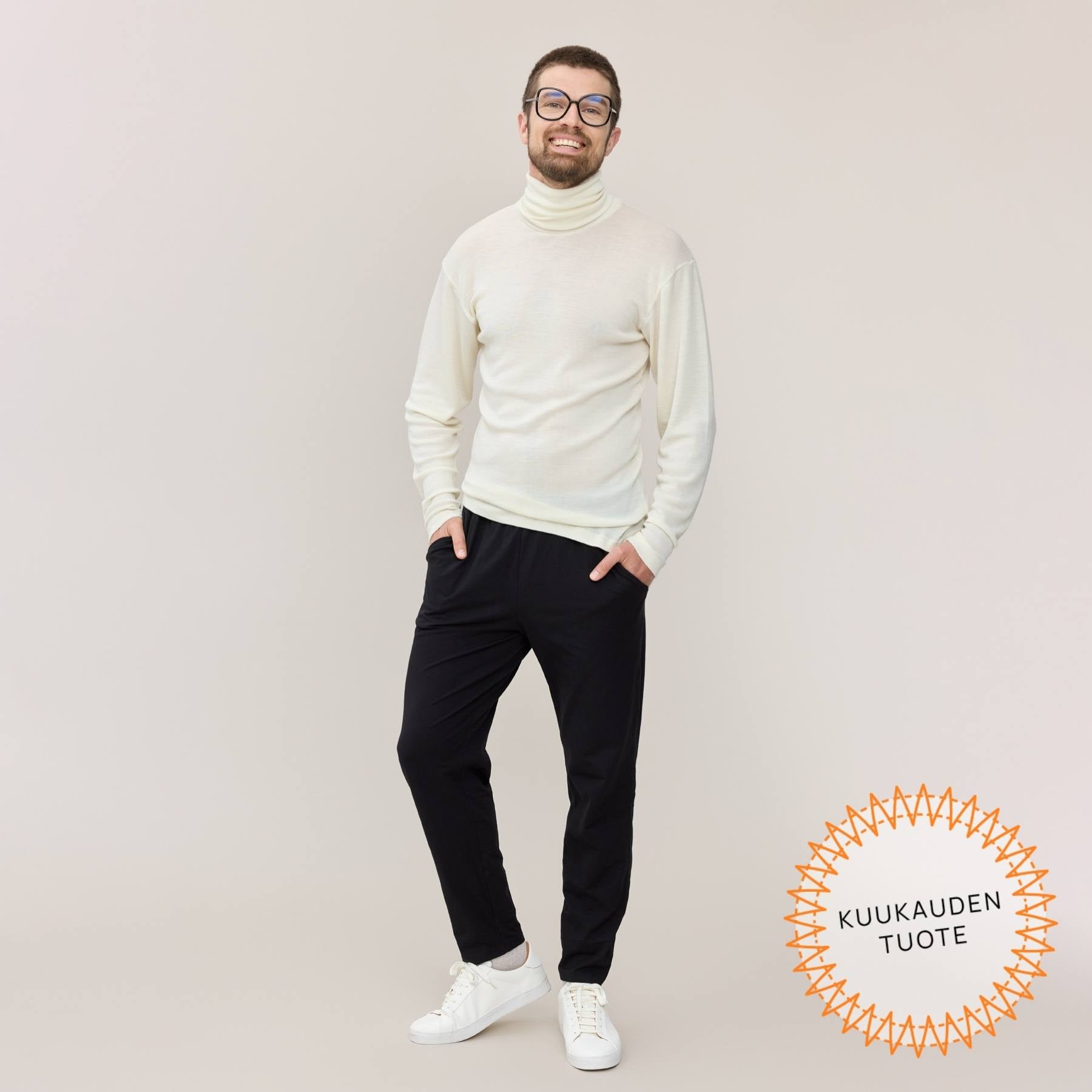 Mustat Jokapaikan housut miehen päällä. Housuissa on pitkä lahje ja taskut molemmilla sivuilla.