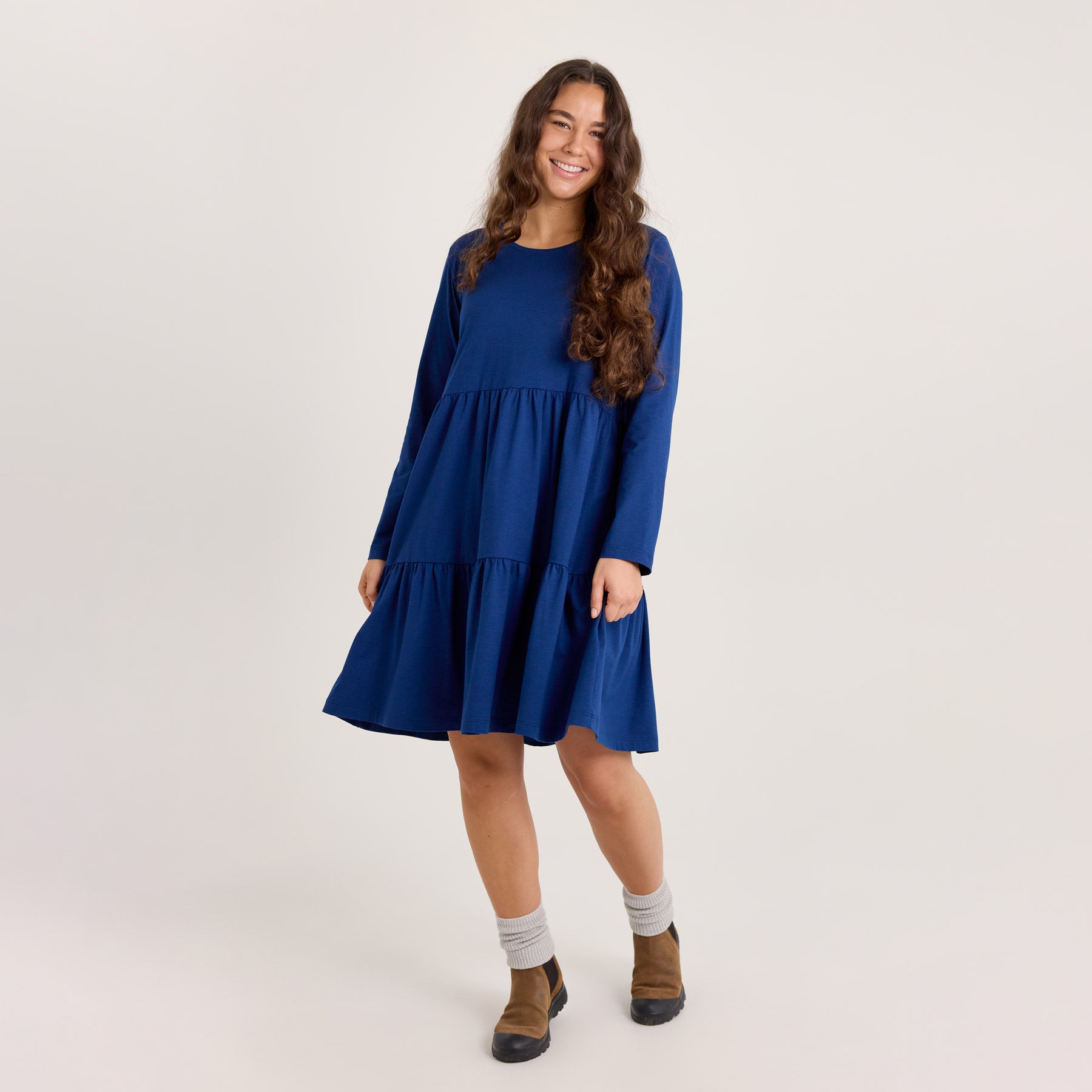 Pitkähihainen frillamekko laivastonsinisenä. Mekko on puettu ruskeiden saappaiden ja paksujen harmaiden sukkien kanssa.