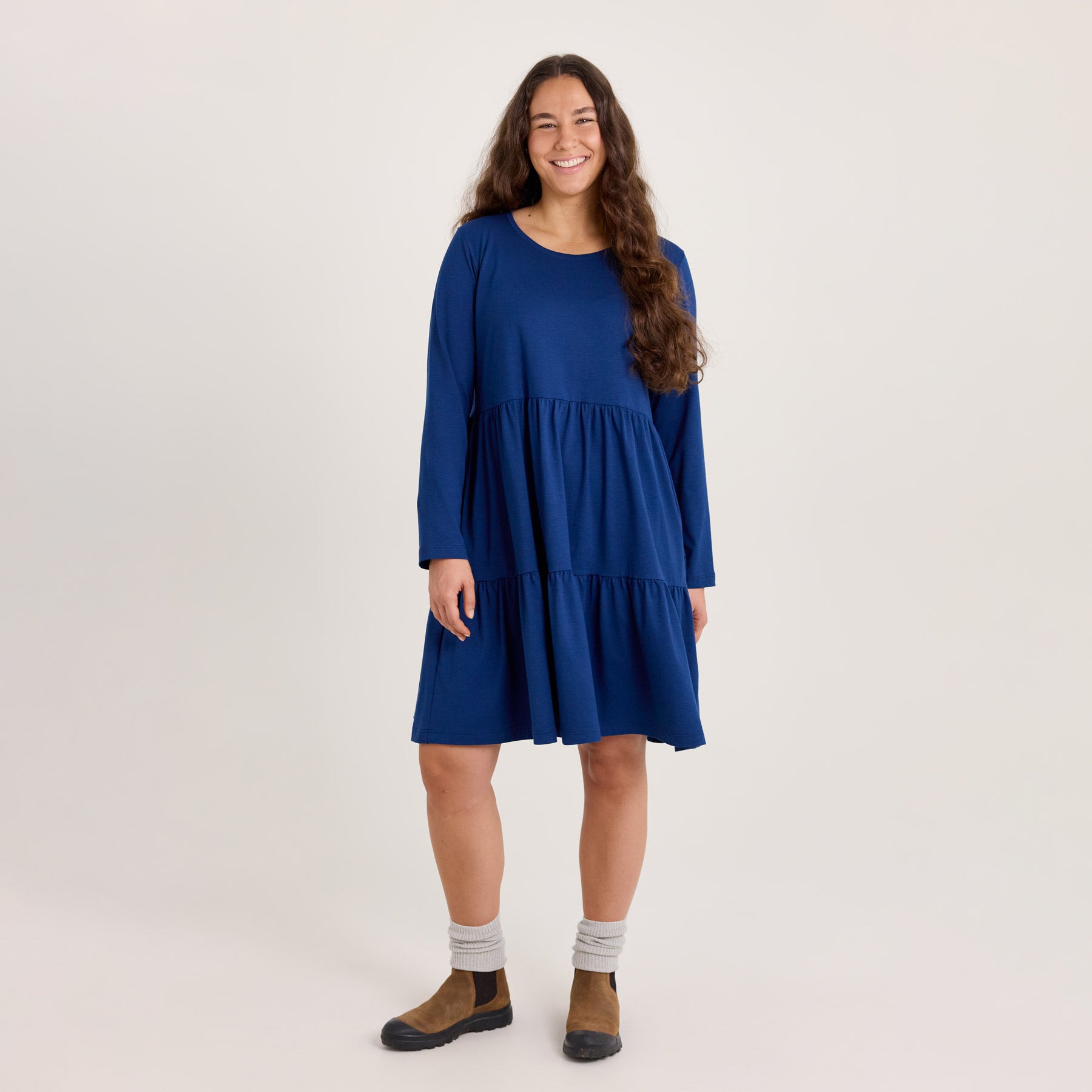 Pitkähihainen frillamekko upeassa laivastonsinisessä värissä. Mekossa on hulmuava helma. Mekossa on kaksi leveää frillakerrosta, ensimmäinen alkaa vyötäröltä.