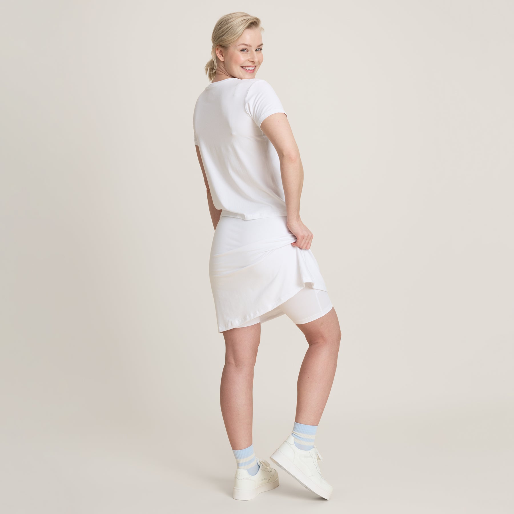 Valkoinen treenihame kuvattuna sivuttain. Hameosuuden alla on shortsit, joissa on taskut.