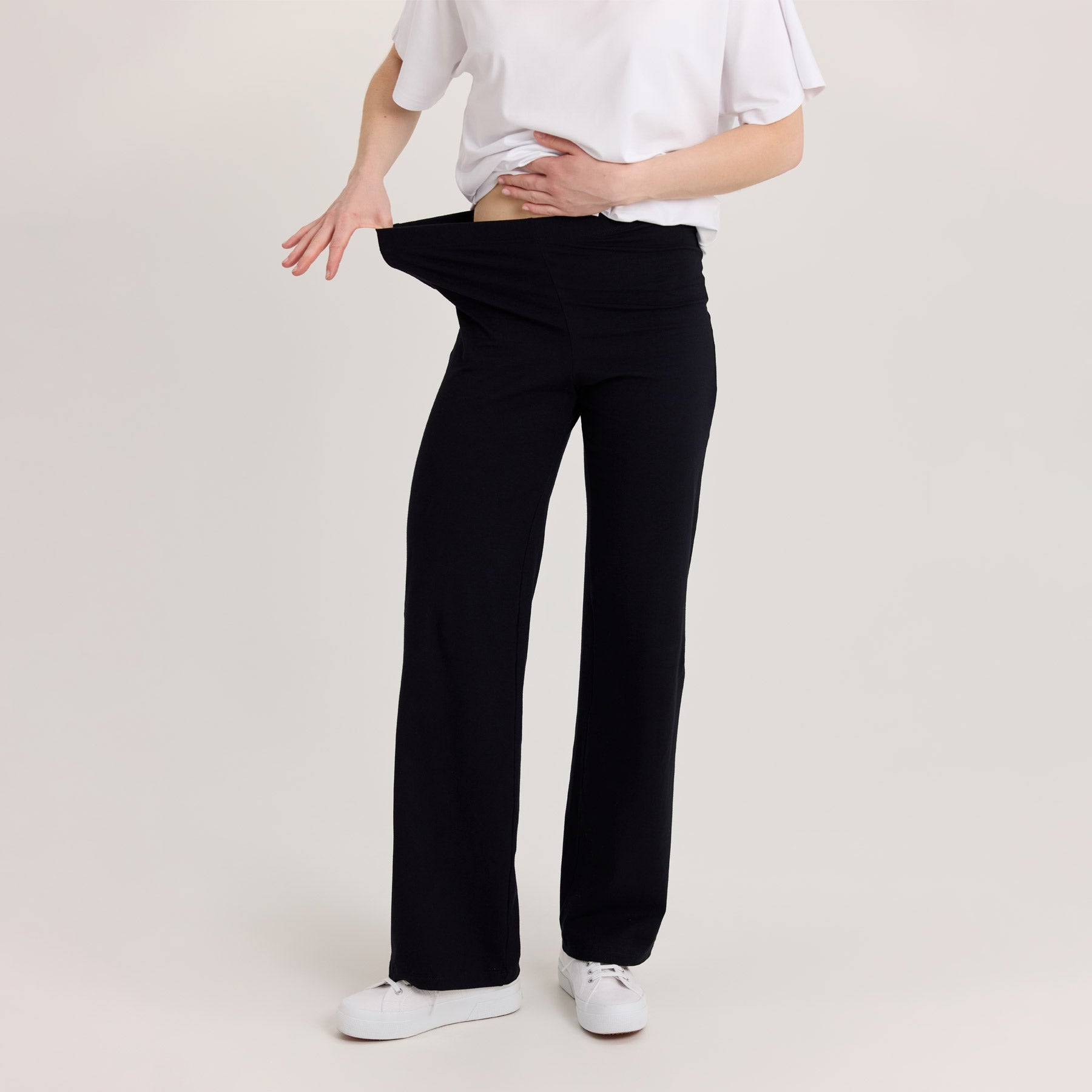 Lähikuva suorista bambuhousuista, malli venyttää vyötärönauhaa, ja esittää että housut ovat joustavat.