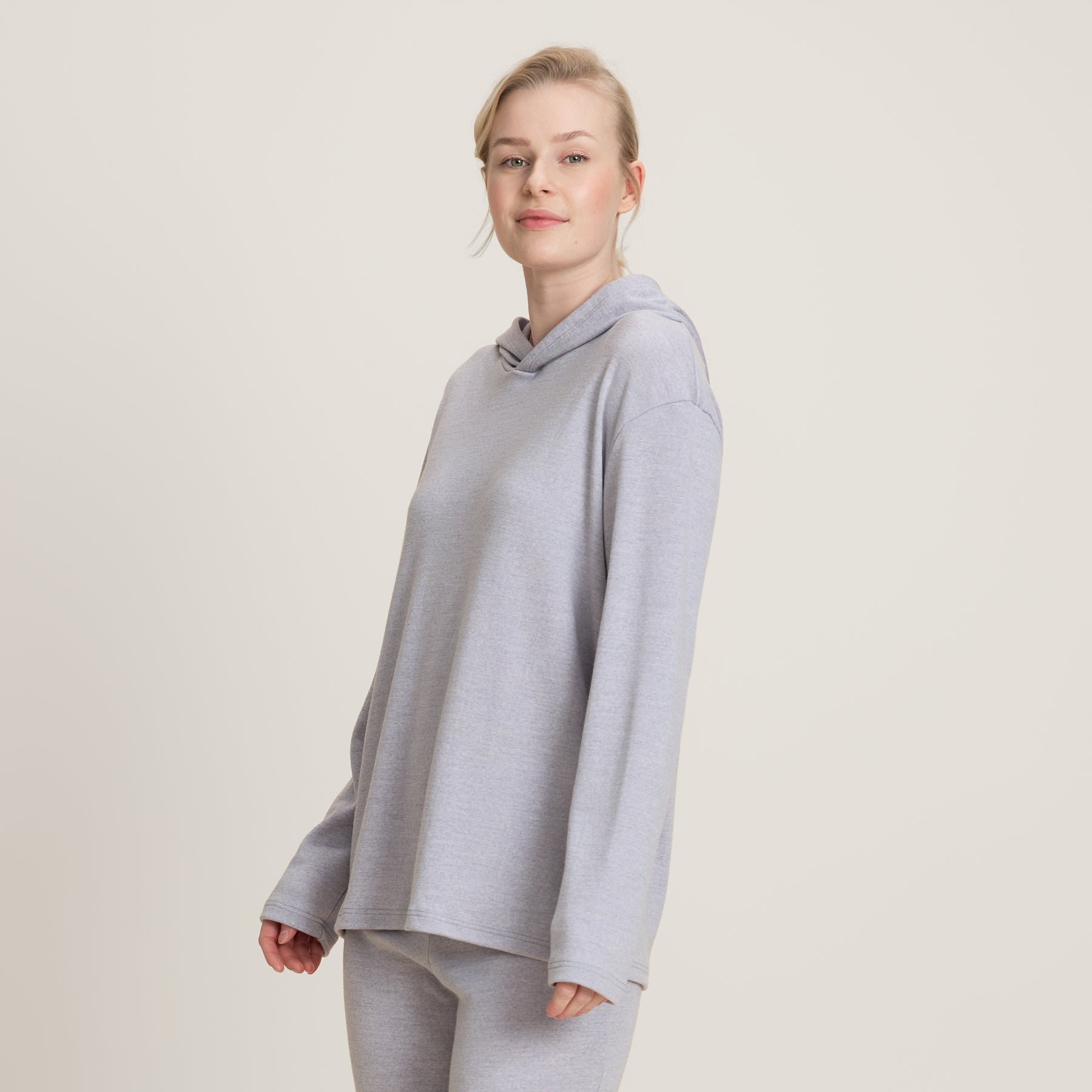 Lähikuva harmaasta suorasta hupparista. Hupparissa on pitkät hihat, malliltaan suora ja hupparissa on huppu.