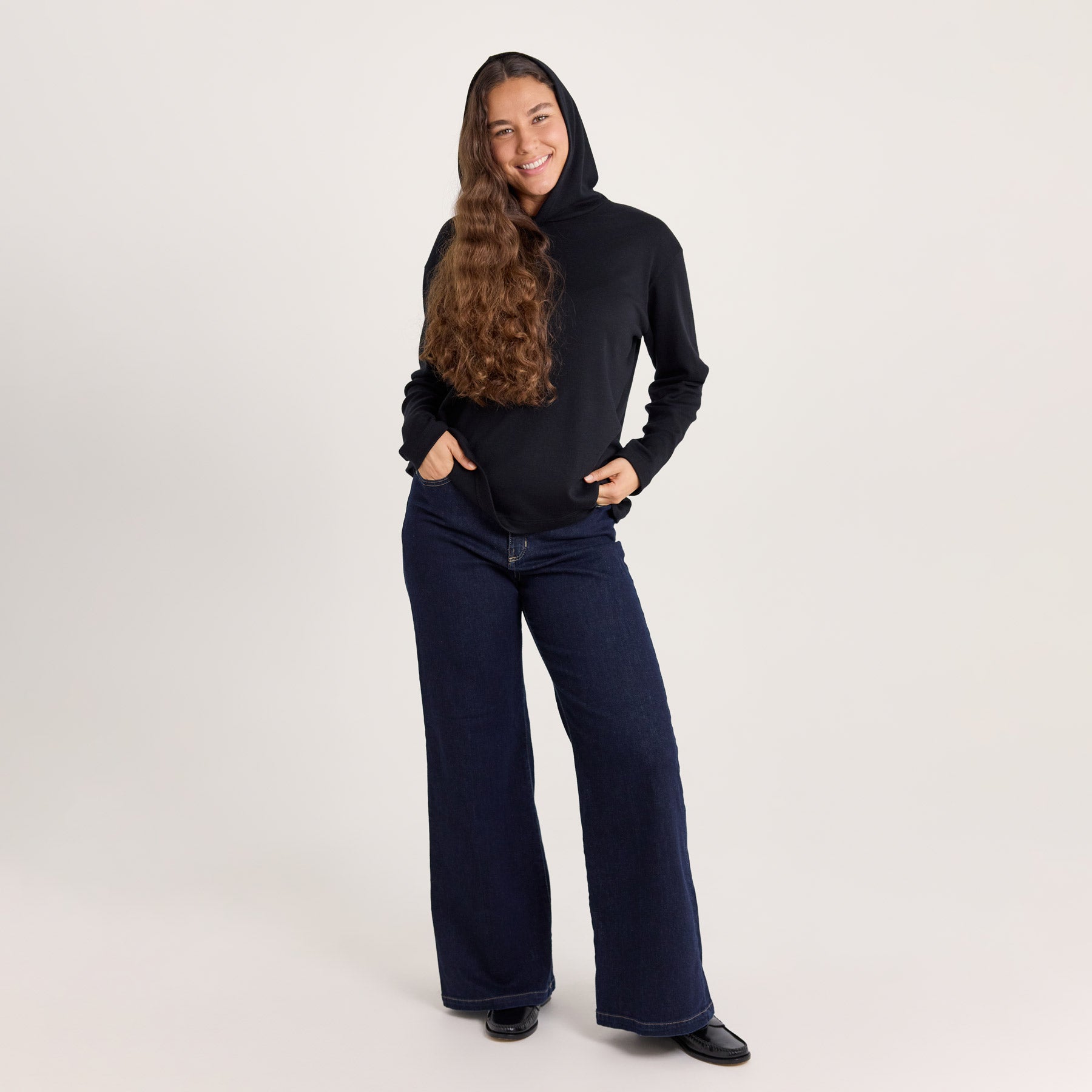 Mustan värinen suora huppari ja tummansiniset leveälahkeiset farkut on rento ja yksinkertainen arkinen asu.