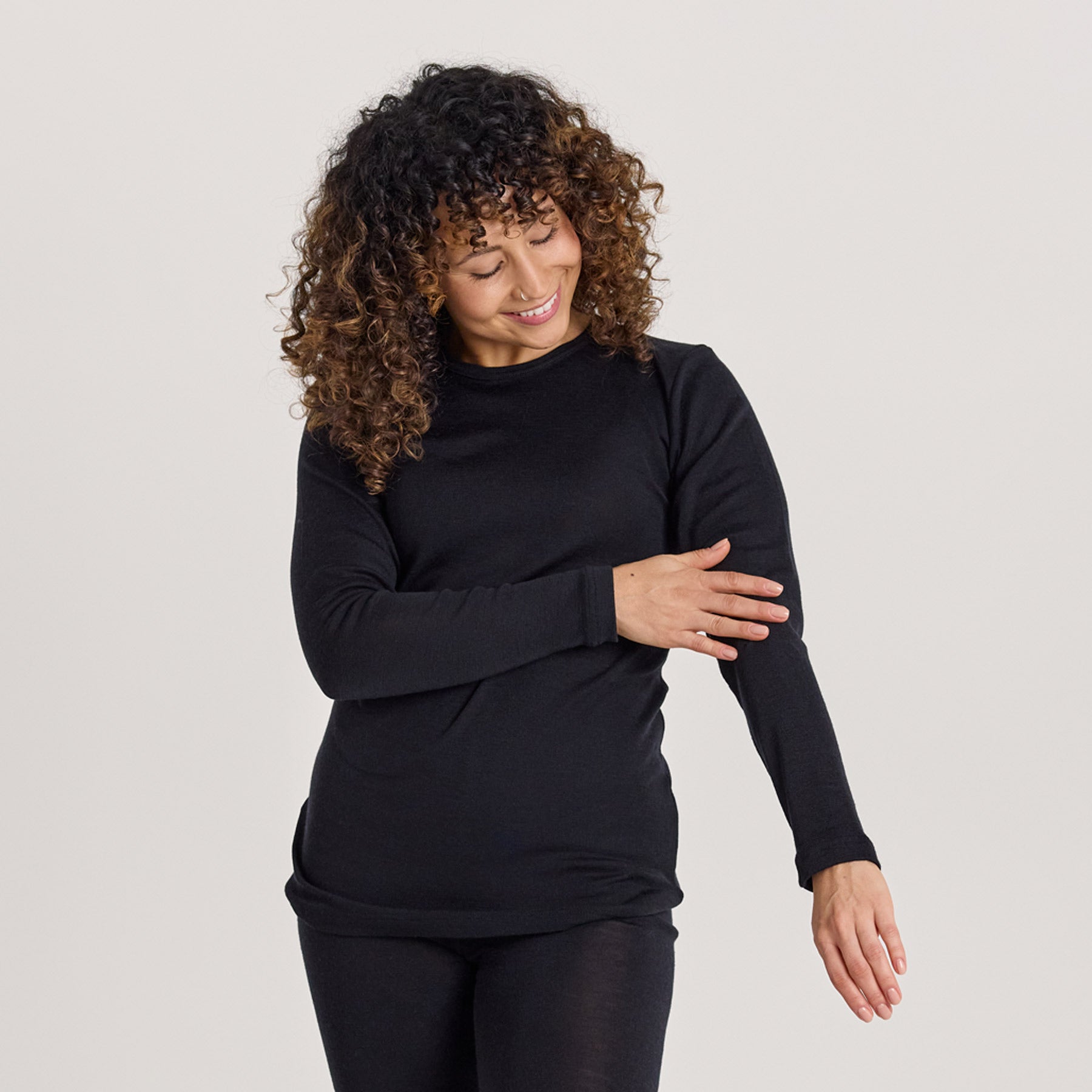 KLASSIKKO pitkähihainen paita on valmistettu pehmeästä merinosilkistä. Kuvassa malli sivelee paidan hihaa, esitellen sen sileää pintaa.