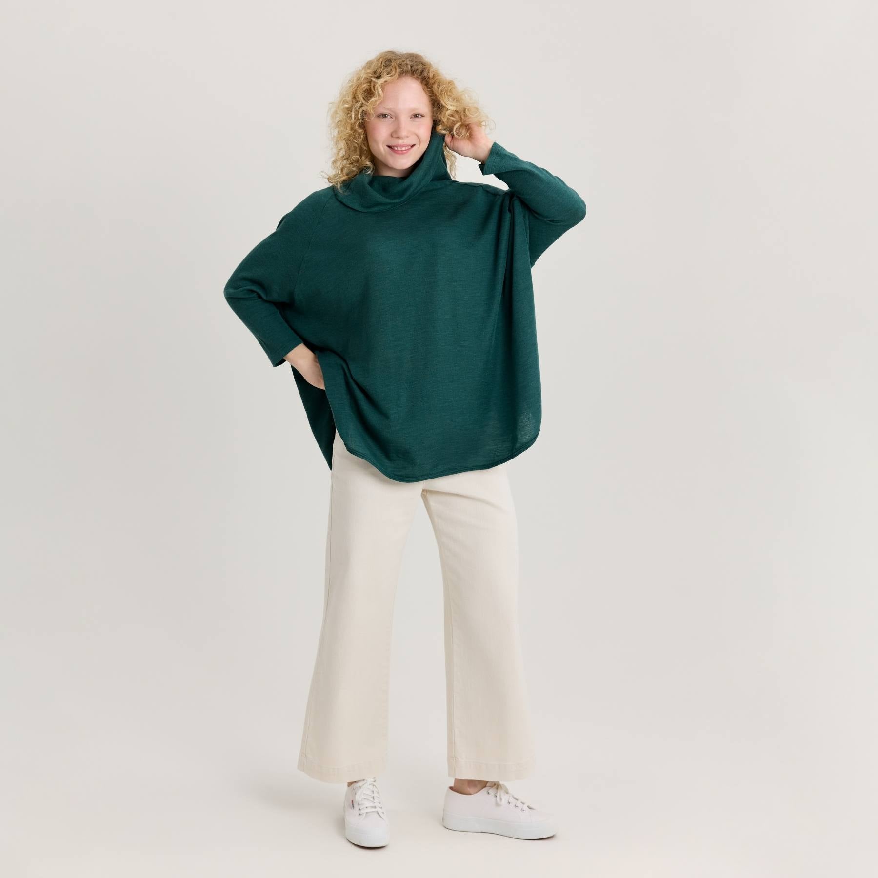 Vihreä neuletunika ja valkoiset leveälahkeiset farkut. Neuletunika on pehmeää ja hengittävää merinosilkkiä.