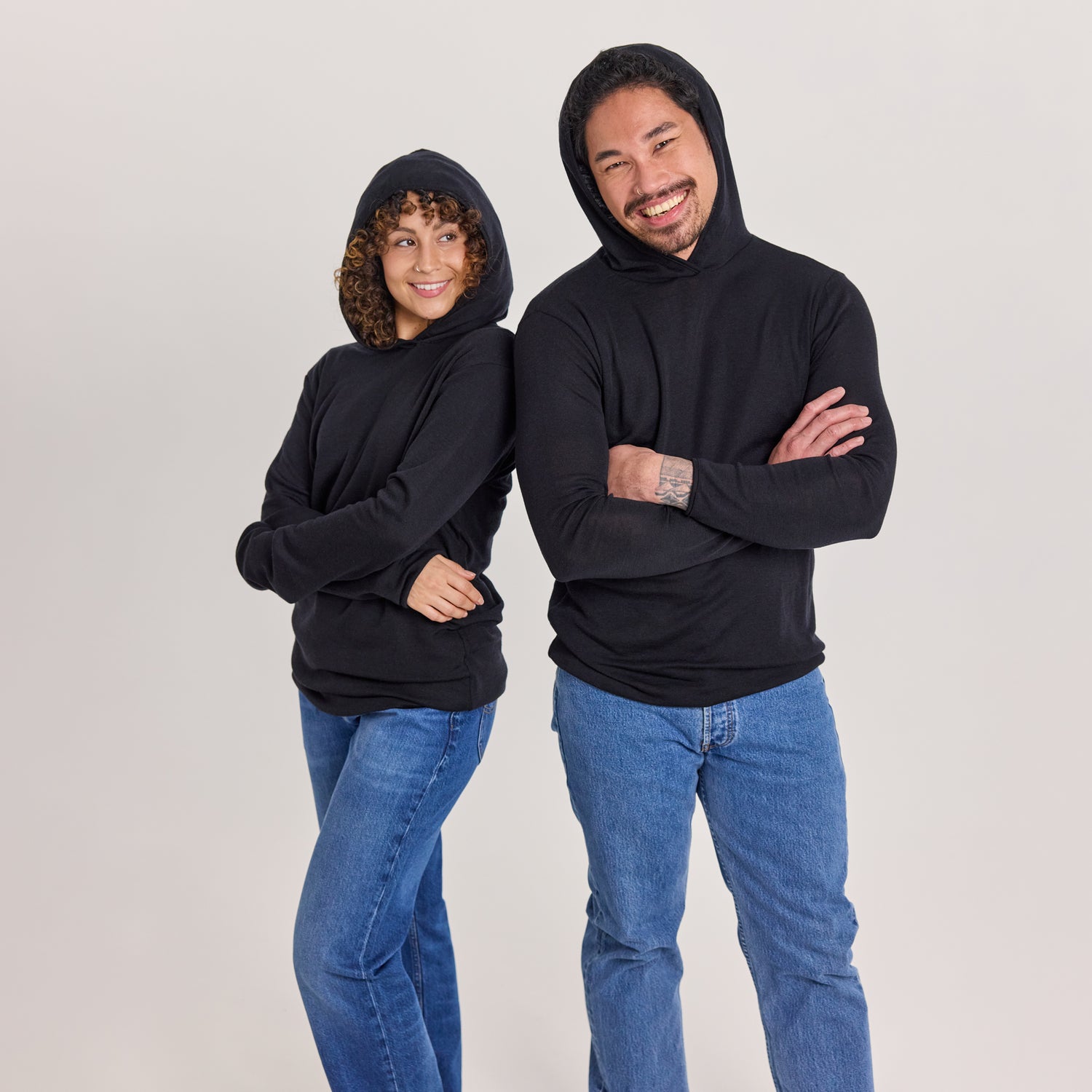 Nainen ja mies mustassa merinosilkkisessä unisex-hupparissa huput päässä.