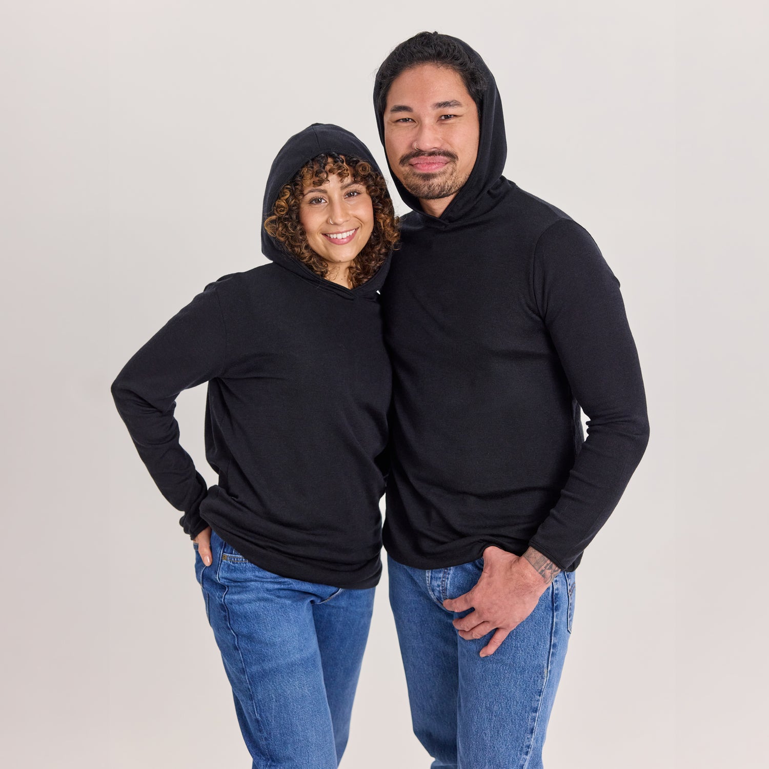 Nainen ja mies mustassa merinosilkkisessä unisex-hupparissa huput päässä.