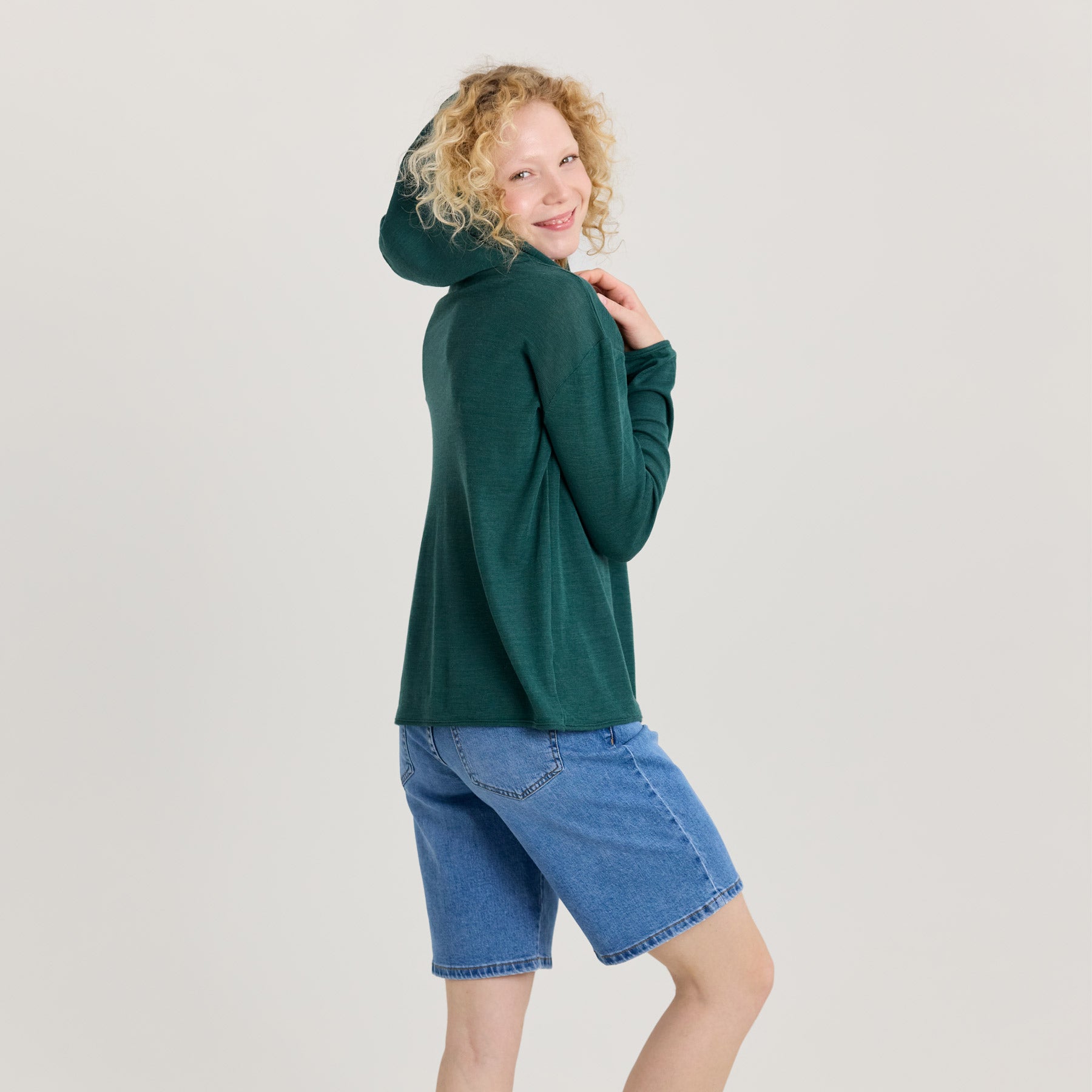 Vihreä unisex huppari kuvattuna sivuttain, jolloin hupun muoto tulee näkyville mallin puettua sen päänsä ylle.