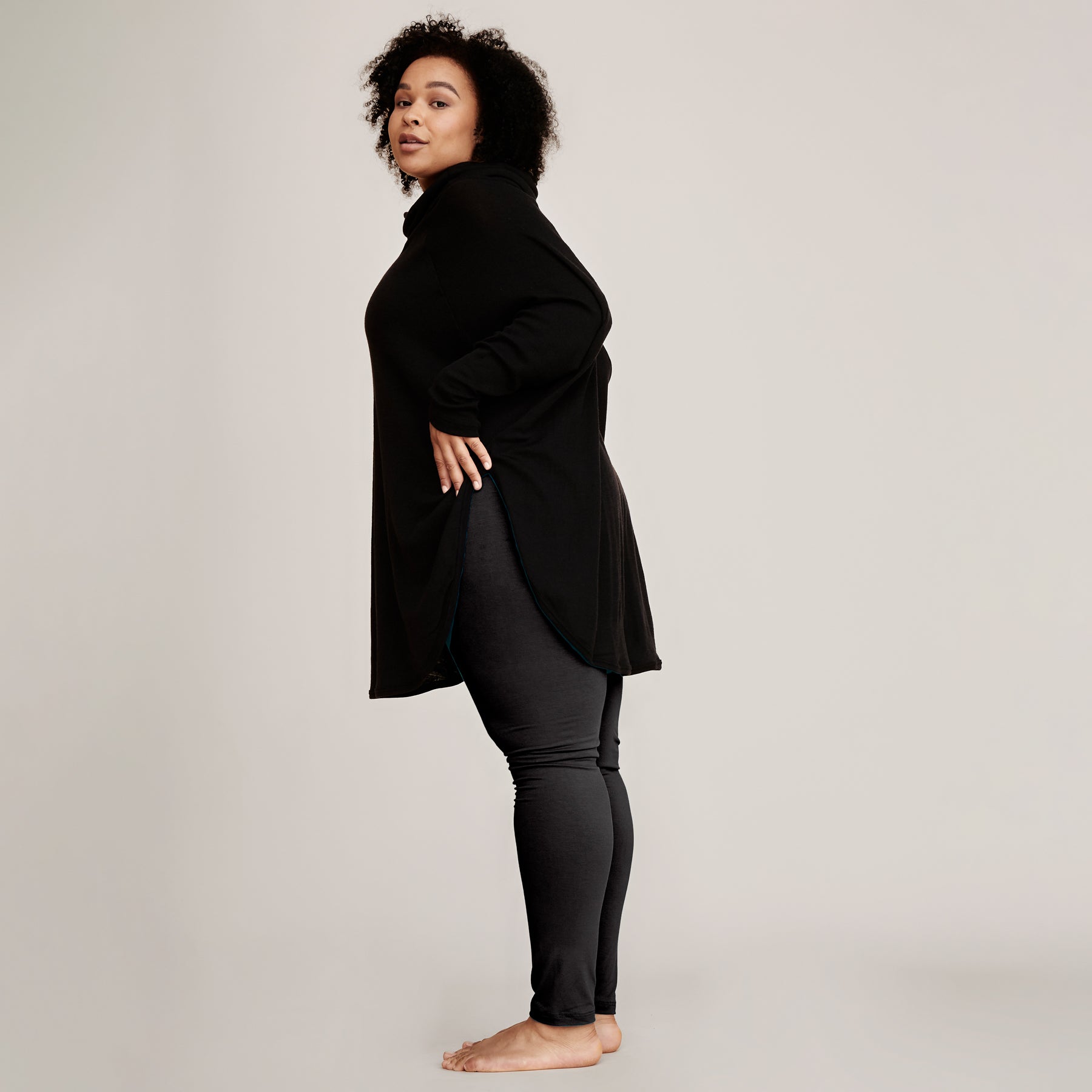 Musta neuletunika yhdistettynä mustiin bambuleggingseihin. Neuletunikassa on sivusaumassa korkea halkio, ja neuleen helma on pyöristetty.