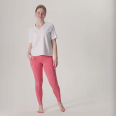 Videolla on korallipinkit LEMPI treenileggingsit ja valkoinen Jokapaikan t-paita. Mallilla on toinen käsi treenileggingsien reisitaskussa.
