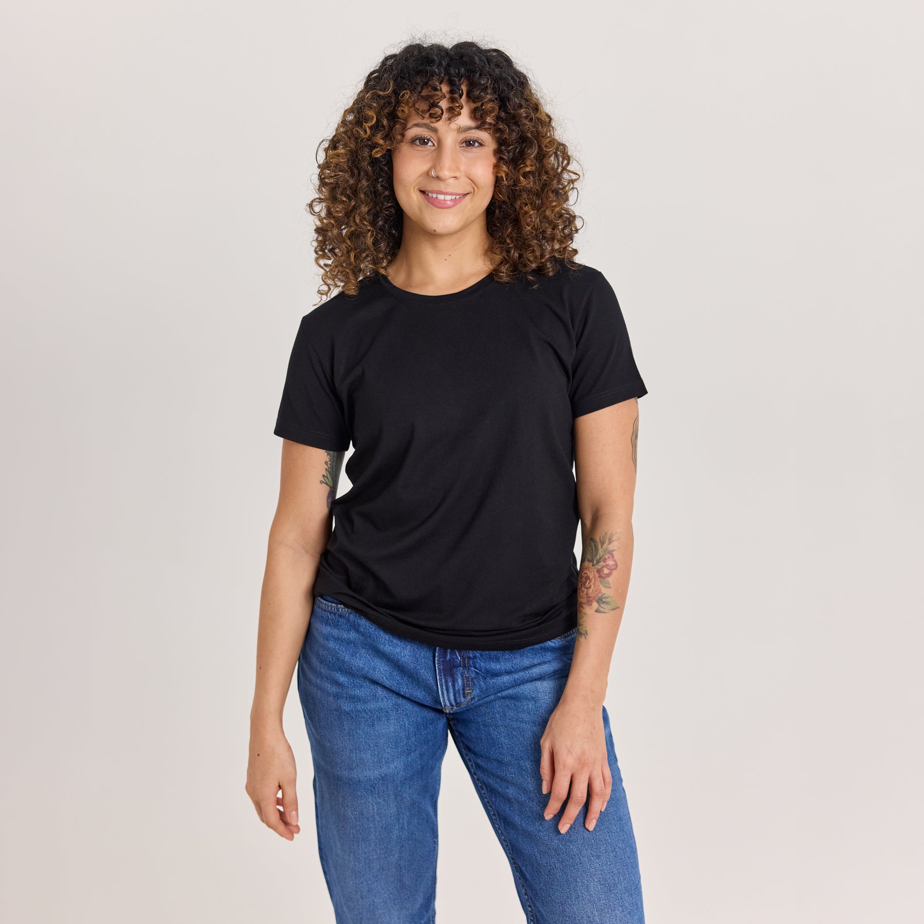 Musta naisten slimmi t-paita ja siniset farkut. Pehmeä, paksu bambuviskoosi istuu vartalolle mukavasti ilman läpinäkyvyyttä.