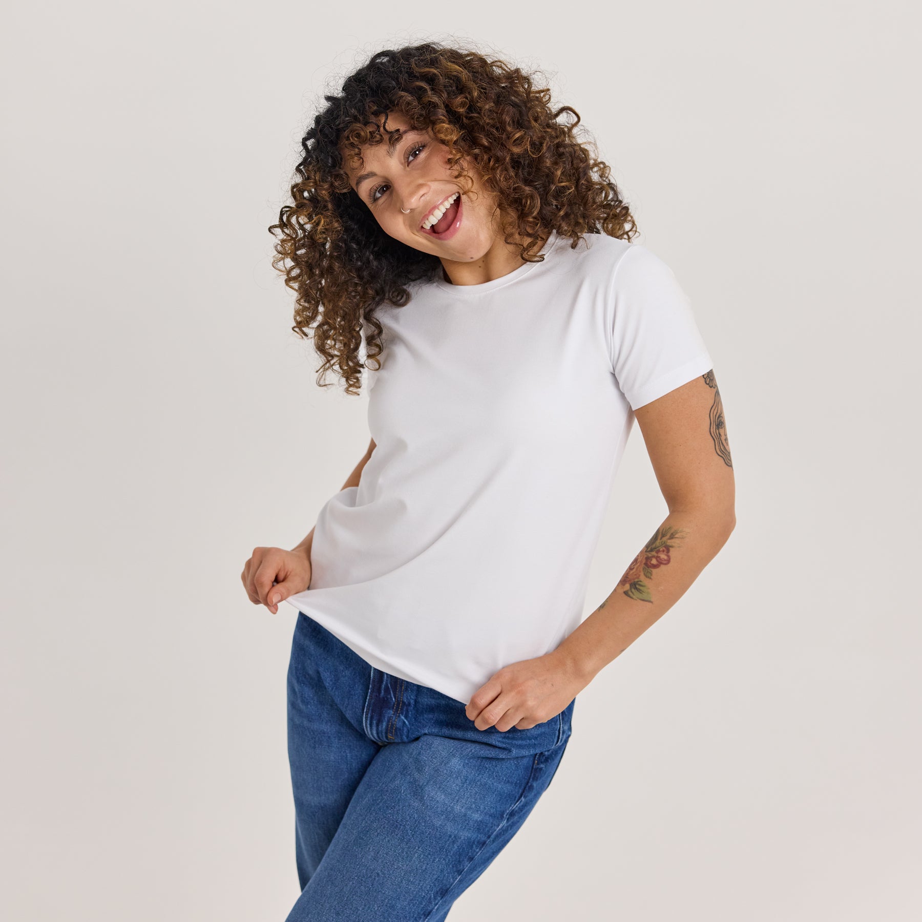 Naisten slimmi t-paita valkoisena. Valmistettu paksusta ja pehmeästä bambuviskoosista. Mallilla on siniset farkut, ja valkoinen t-paita, joka on täydellinen perusasu kerrospukeutumiseen.