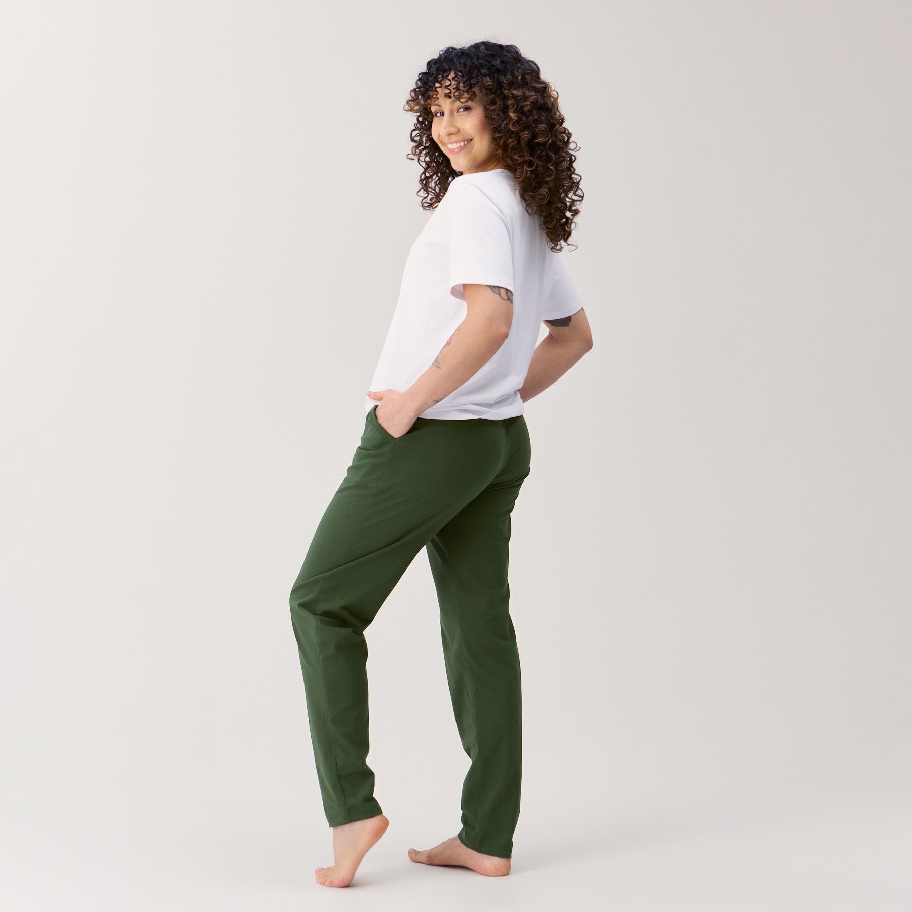 Maastonvihreät Jokapaikan housut kuvattuna takaa sivuttain, jolloin housujen takaosa näkyy kuvassa. Mallilla on kädet taskuissa.