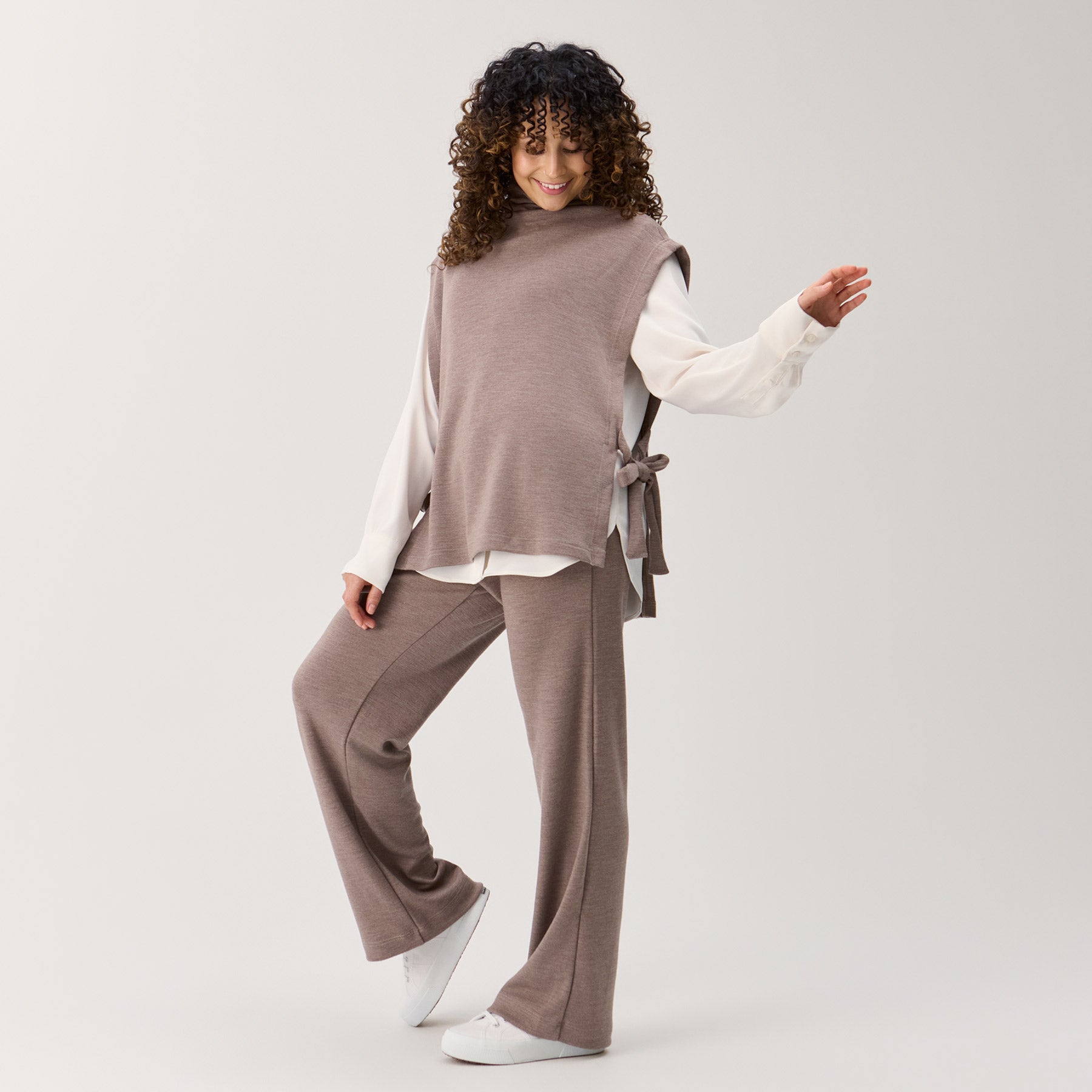 Meleeratun beigen värinen liivikauluri ja rennot neulehousut. Liivikaulurin alla on valkoinen kauluspaita.