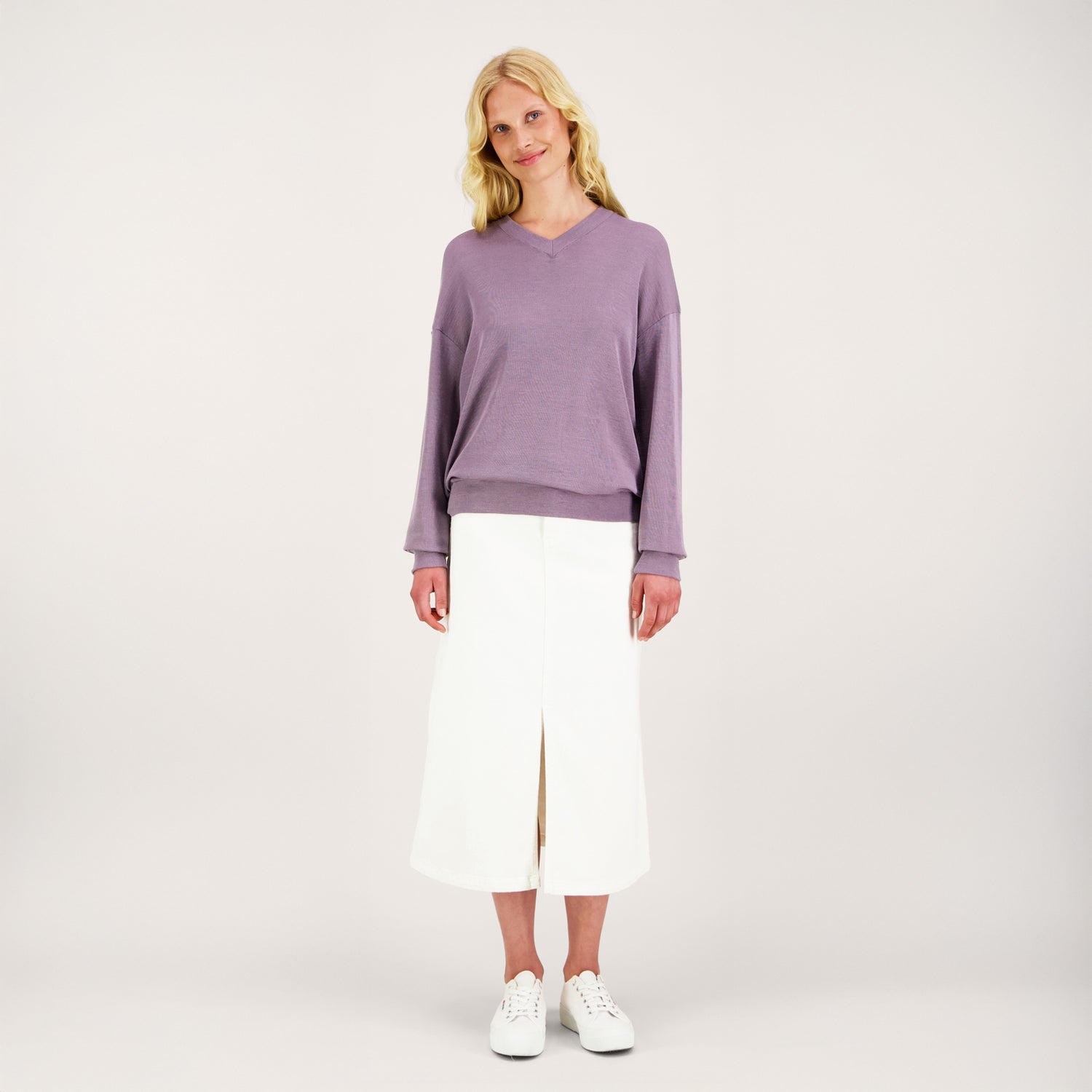 Unisex-mallinen KLASSIKKO -neulepaita naisen päällä. Paidassa on v-pääntie, pitkät hihat ja väljä istuvuus.