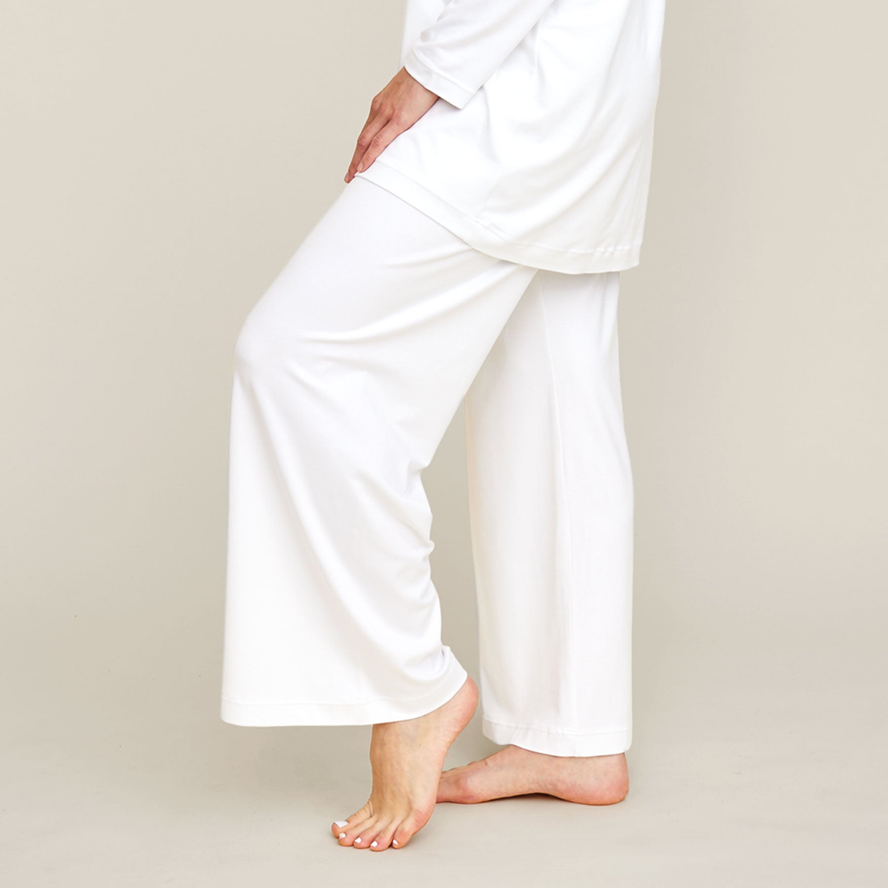 Lähikuva valkoisista pyjamahousuista. Housut ovat malliltansa väljät ja lahkeet ovat leveät.