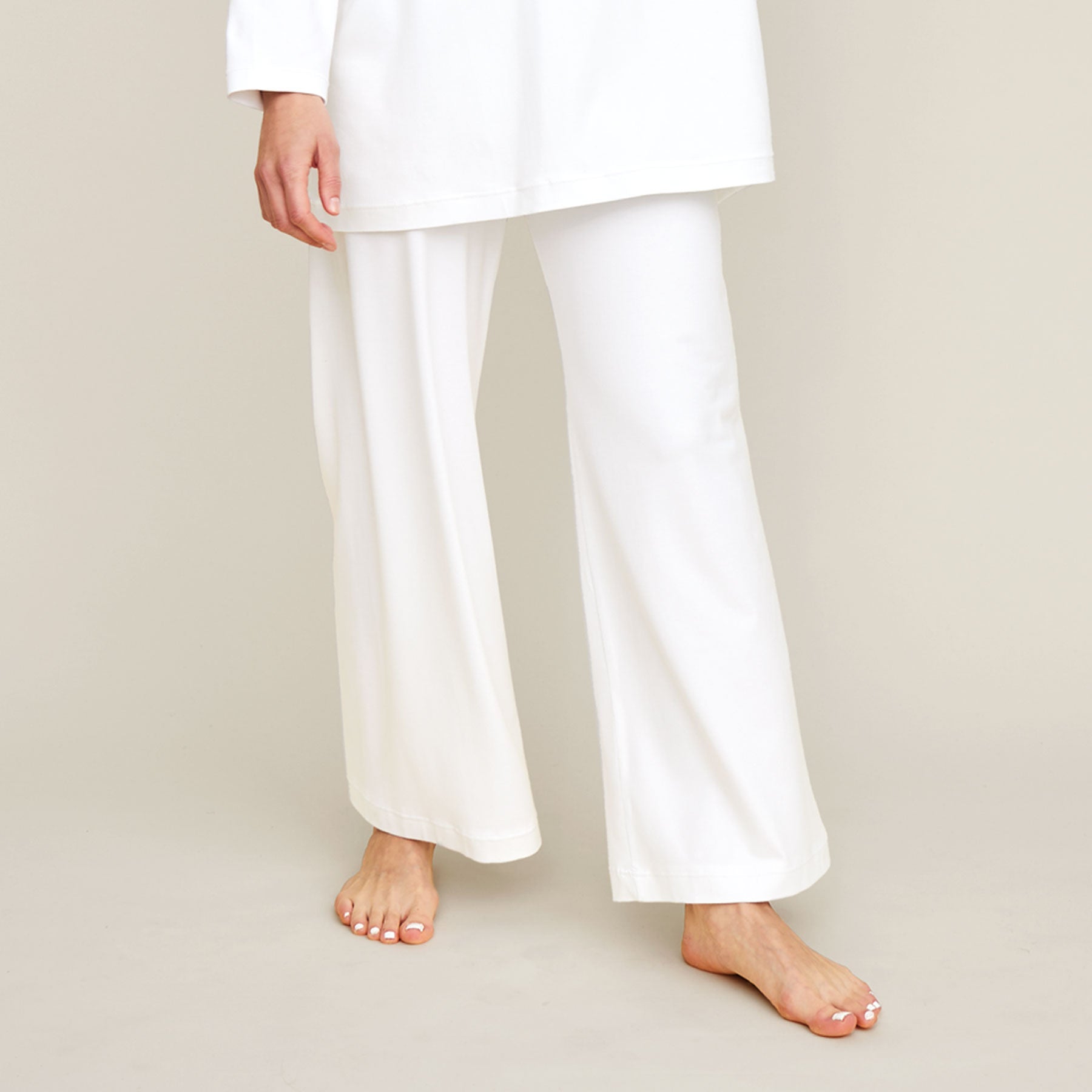Lähikuva valkoisista pyjamahousuista. Housut ovat malliltansa väljät ja lahkeet ovat leveät.